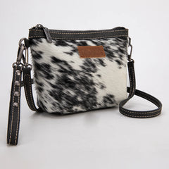 Wrangler genuine hair-on cowhide crossbody wristlet with black PU leather trim, detachable strap, and natural black-and-white hide pattern.