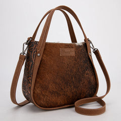 Wrangler genuine hair-on cowhide crossbody and tote bag in brown, featuring natural cowhide texture, dual top handles, adjustable shoulder strap, and rustic Western leather patch