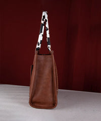 Side view of Wrangler cow print purse showing slim profile and dual cowhide-style handles