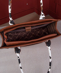 Top view of Wrangler cow print purse showing spacious interior with zipper pocket, divider, and quilted lining