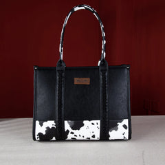 Wrangler cow print purse in color black with concealed carry pocket, whipstitch details, and signature Wrangler logo. Secure zipper top. 
