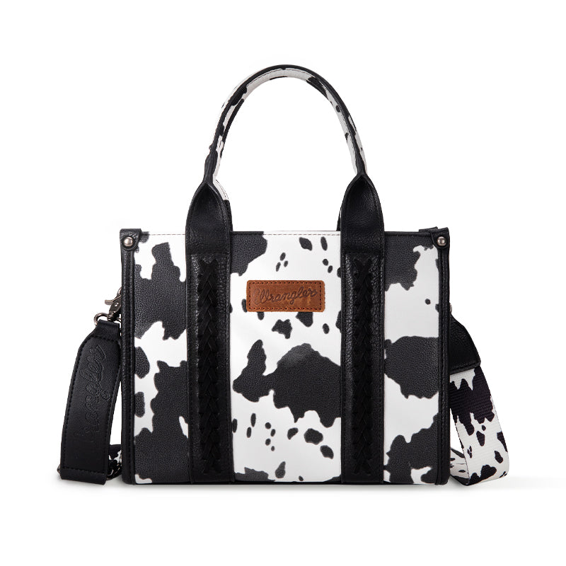 Black and white cow print handbag with a strap on a white background